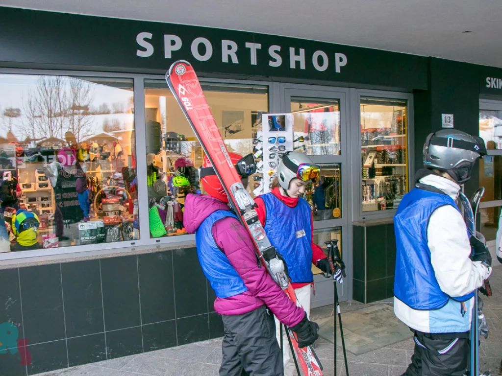 Jugendliche stehen mit Skiern vor einem Sportgeschäft.